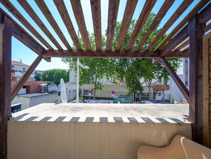 Un espacio al aire libre techado con vista a un estacionamiento y edificios al fondo.