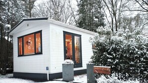A small, white, single-story building with large windows and a snow-covered landscape. - Vrbo Property (Putten)