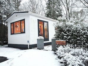 Een klein, wit, laag gebouw met grote ramen en een besneeerd landschap.