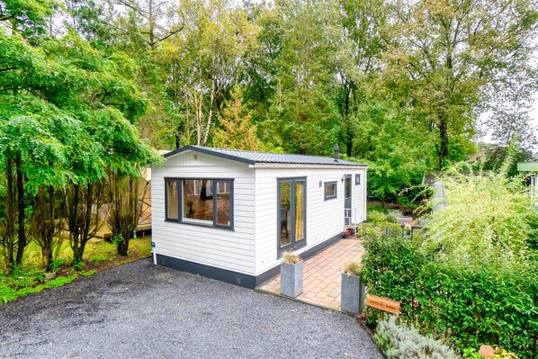 Een klein, laag huis met een grindpad en een tuin.