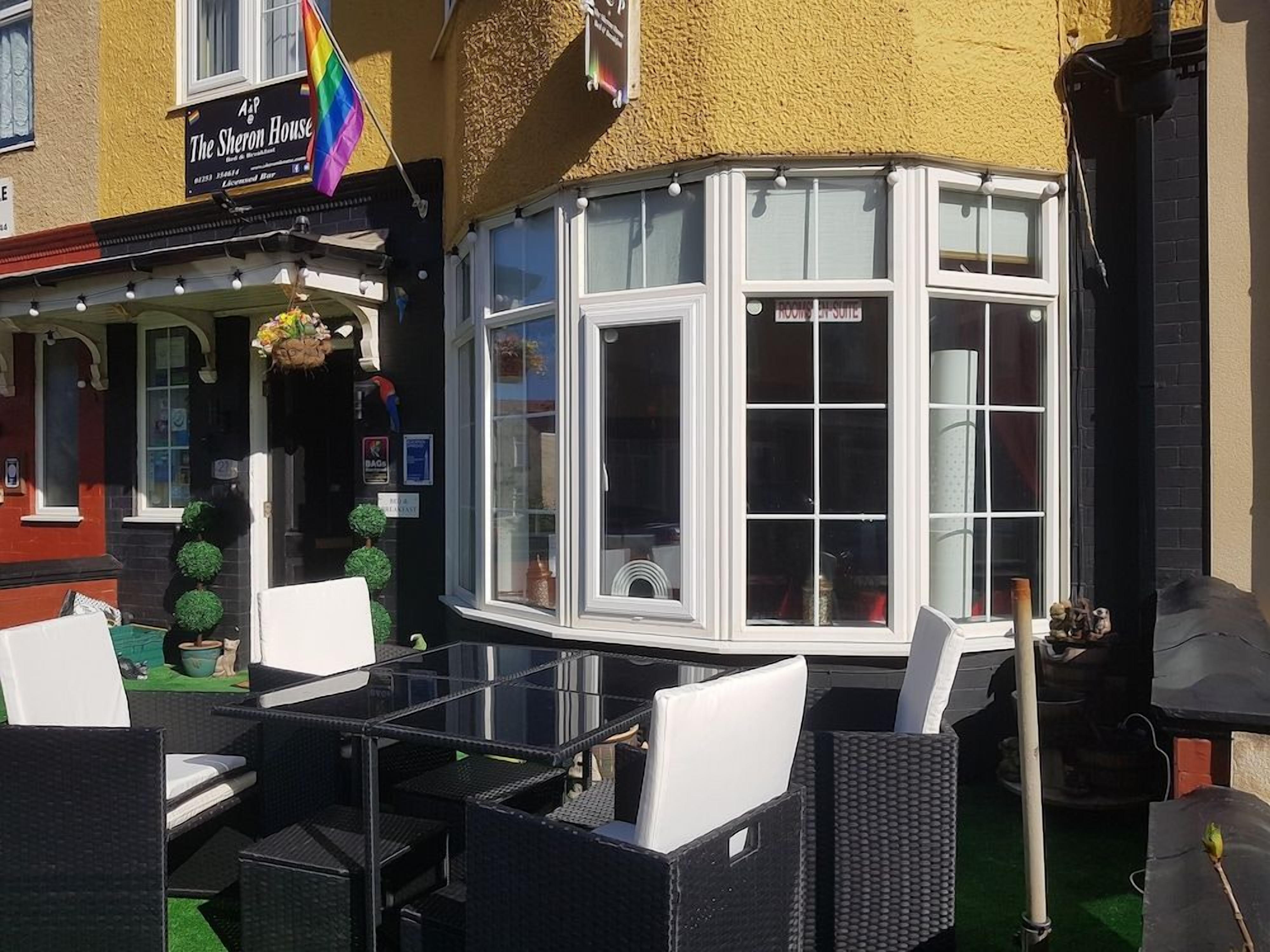 A corner room with a bay window, outdoor seating with wicker furniture, and a sign for 'The Sheridan House.'