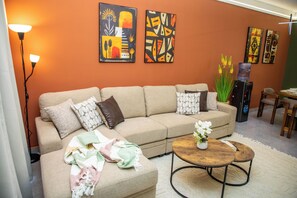 Ein Wohnzimmer mit einem beigen Sofa, einem runden Couchtisch und einem Wasserspender.