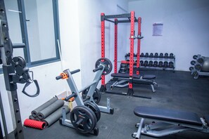 Ein Fitnessraum mit Gewichthebern, Kurzhanteln und einer Trainingsbank.