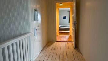 Un corridoio con pavimento in legno e pareti bianche, che conduce a una stanza con un letto.