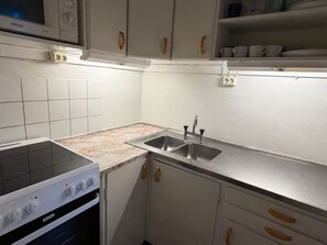 A kitchen with white cabinets, a stove, a sink, and a microwave.