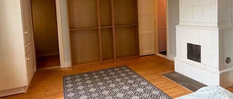 Une pièce avec un plancher en bois, un tapis à motifs, une cheminée blanche et un placard à portes coulissantes.