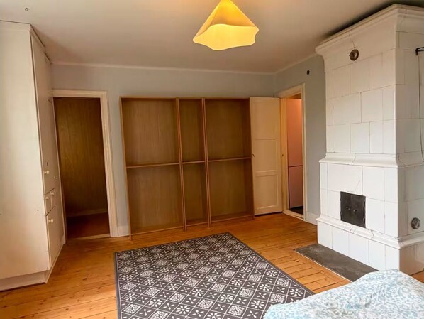 A room with a wooden floor, a patterned rug, a white fireplace, and a sliding door closet.