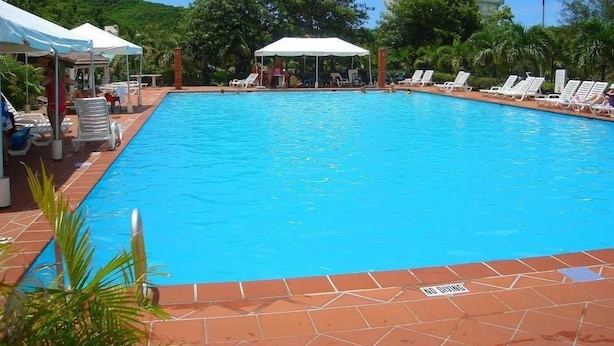 A swimming pool with lounge chairs and umbrellas, surrounded by greenery. - HBK Villa Rentals (Jolly Harbour)