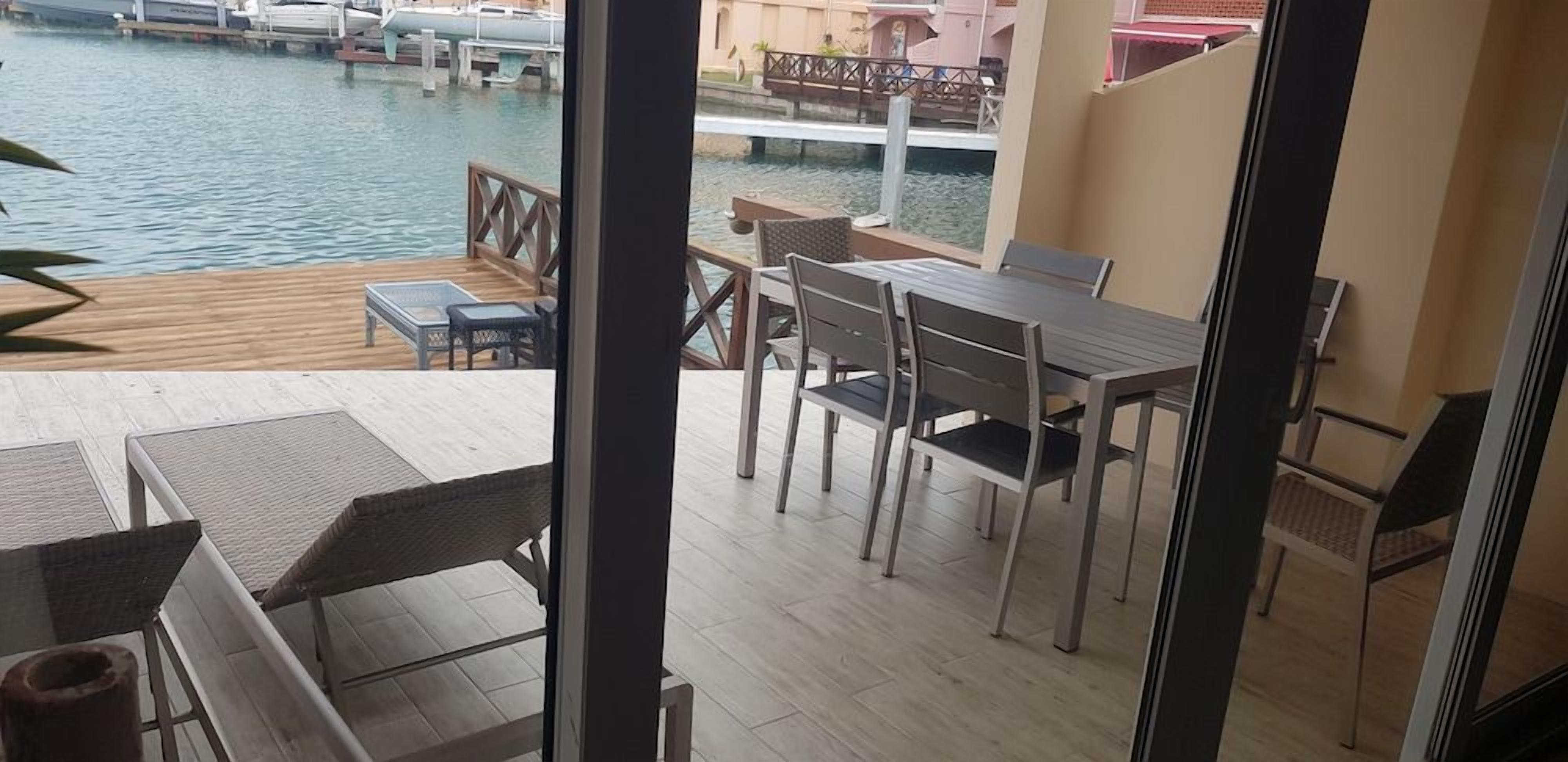 A balcony with a view of a marina, a table with chairs, and a wooden deck.