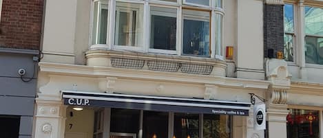 A building with a classical architectural style, featuring a prominent bay window and a storefront with a sign that reads 'C.U.P. Specialty coffee & tea.'