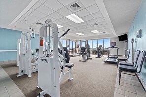 Ein Fitnessstudio mit verschiedenen Trainingsgeräten, Laufbändern und Sitzbereichen.