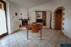A dining area with a wooden table and chairs, a fireplace, a radiator, and a tiled floor. - Experience the magic of Tuscany in Casole d'Elsa, located between Siena, San Gimignano, and Chianti (Casole d'Elsa)