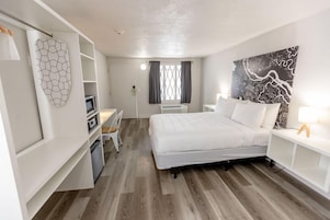 Un dormitorio moderno con cama, escritorio y armario.
