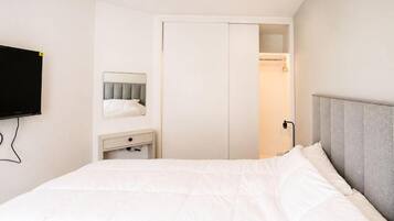 Un dormitorio con cama, mesita de noche, espejo y armario.