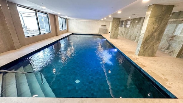 An indoor swimming pool with clear water, surrounded by walls with a marble-like texture. - Executive Suite with Swimming Pool & Gym (Gibraltar)