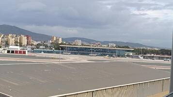 Una terminal de aeropuerto con un espacio amplio, un edificio de techo plano y un paisaje montañoso de fondo.