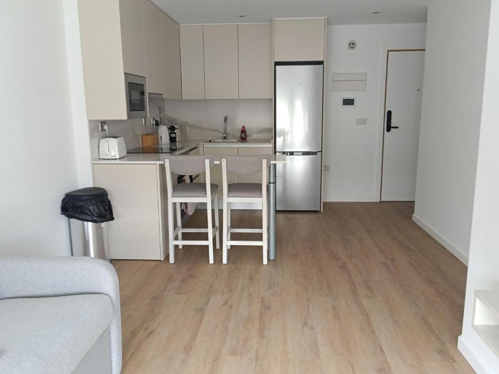 Una cocina compacta con nevera, un lavabo y una zona de comedor con dos sillas.
