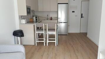 Una cocina compacta con nevera, un lavabo y una zona de comedor con dos sillas.