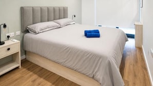 A modern bedroom with a bed, bedside table, and a nightstand. - Executive Suite with Swimming Pool & Gym (Gibraltar)