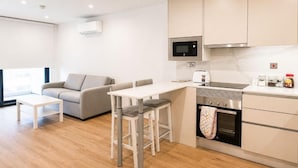 A modern kitchen with a microwave, oven, and bar stools. - Executive Suite with Swimming Pool & Gym (Gibraltar)