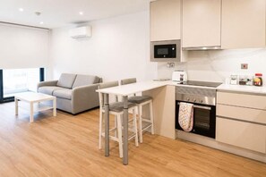 Cozinha moderna com micro-ondas, forno e banquetas.