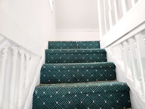 A staircase with green carpeted steps and white balusters.
