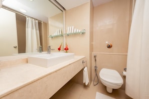Un baño moderno con un espejo grande, un lavabo, un inodoro y una ducha.