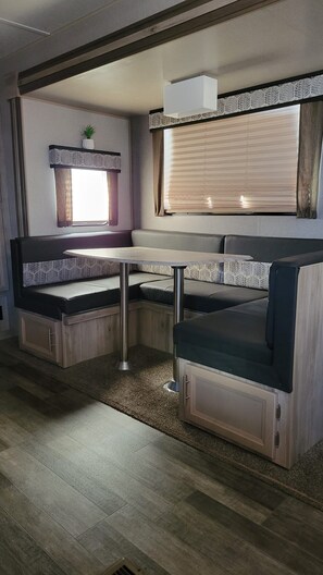 A compact RV interior with a kitchenette, seating area, and a window with blinds. - Cozy 2-bedroom trailer with in wonderful Port Isabel. Indoor/outdoor pool & gym. (Port Isabel)