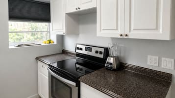 Cozinha com armários brancos, fogão preto e bancada de granito.