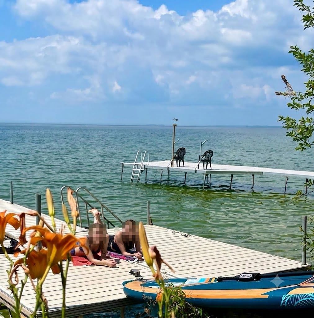 A wooden dock extending into a calm body of water with a clear sky above.