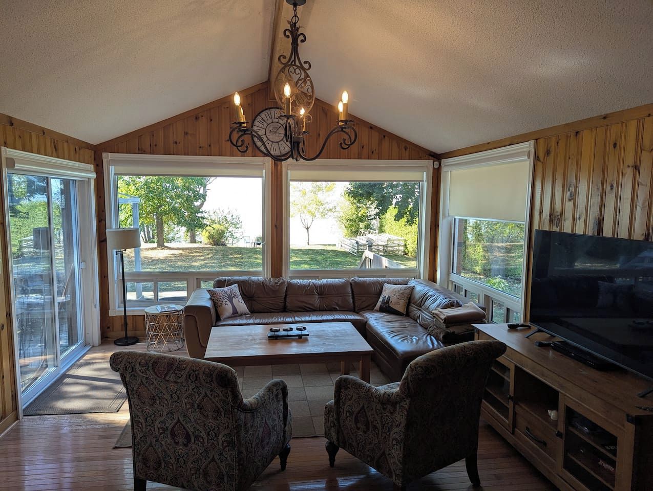 A spacious living room with a large sectional sofa, a coffee table, and a television on a wooden stand.