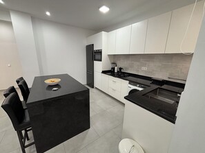 A modern kitchen with a black countertop, white cabinets, and a built-in dishwasher. - Spacious 2-Bedroom Apartment with Air Conditioning Near Laginha Beach (Mindelo)