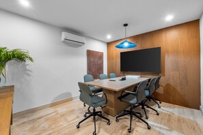 A conference room with a long table, six chairs, a large flat-screen TV, and a blue pendant light. - Jacana | Luxury Resort + Infinity Pool (Bucerías)