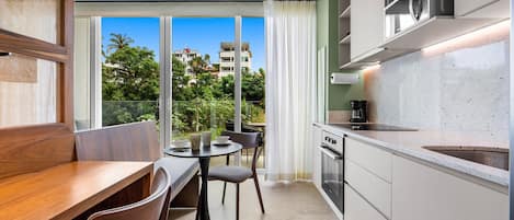 A modern kitchen with a dining area, large windows, and a view of buildings.