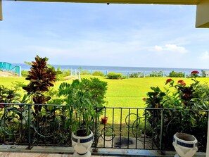 A balcony with a view of a well-maintained lawn and a distant body of water. - Cozy 1-bedroom apartment in fabulous Ocho Rios with AC (Ocho Rios)