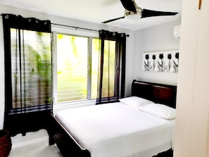 A bedroom with a bed, a ceiling fan, and a window with curtains. - Cozy 1-bedroom apartment in fabulous Ocho Rios with AC (Ocho Rios)