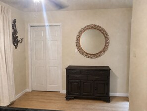 A room with a white door, a dark wooden dresser, and a round mirror with a decorative frame. - La Casa del Río 4BR Retreat with Private River Access & Fire Pit (Dallas)