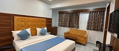 A modern bedroom with a large bed, a sofa, a TV, and a ceiling fan.