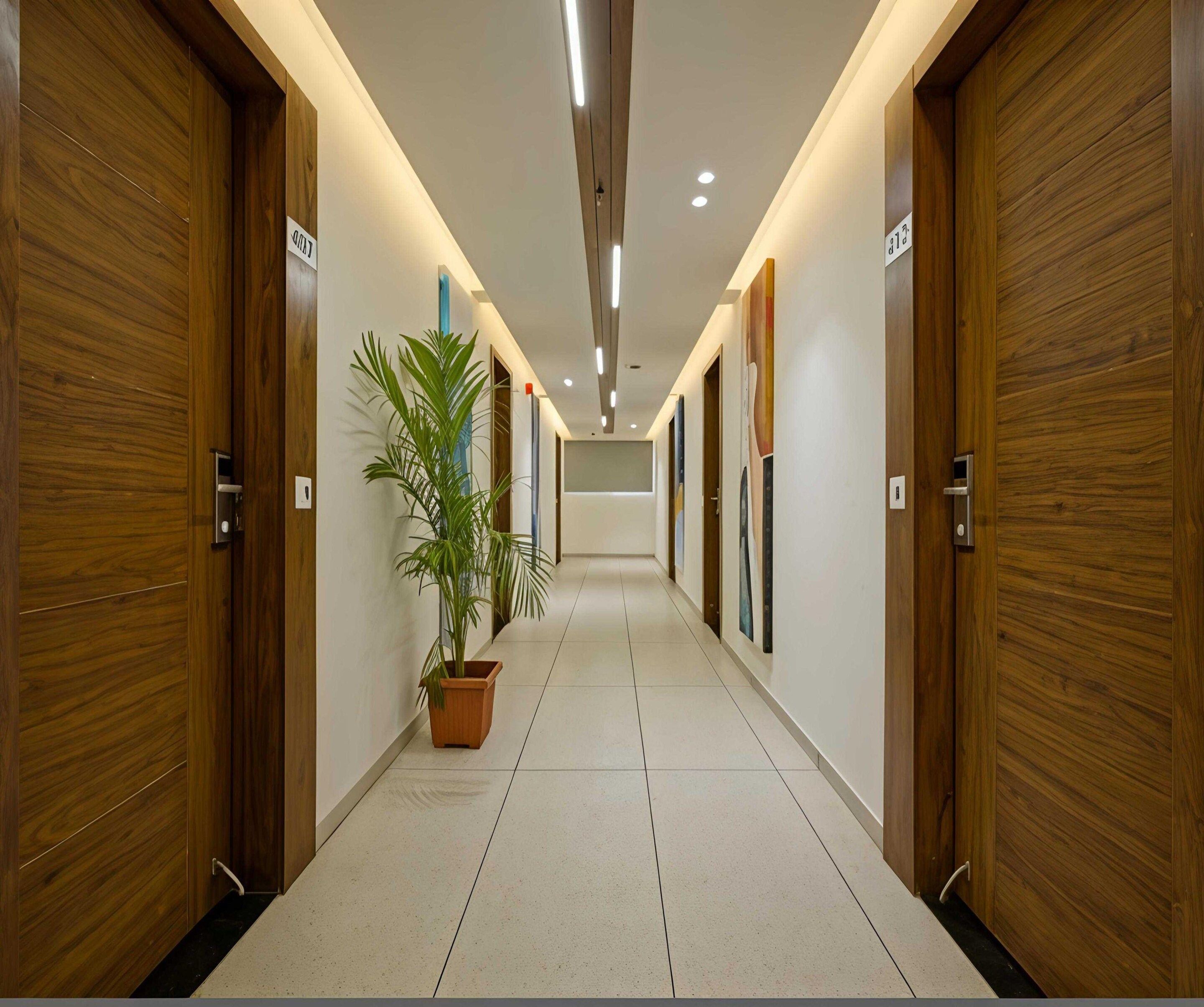 A hallway with wooden doors, potted plants, and recessed lighting.