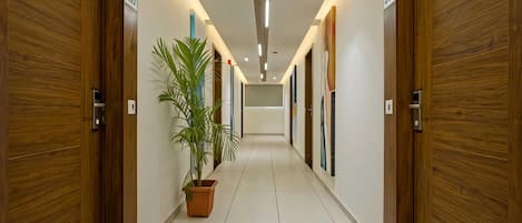 A hallway with wooden doors, potted plants, and recessed lighting.