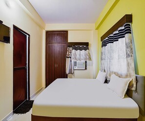A bedroom with a bed, a wardrobe, and curtains. - Deluxe Hotel Blue Velvet (Danapur)