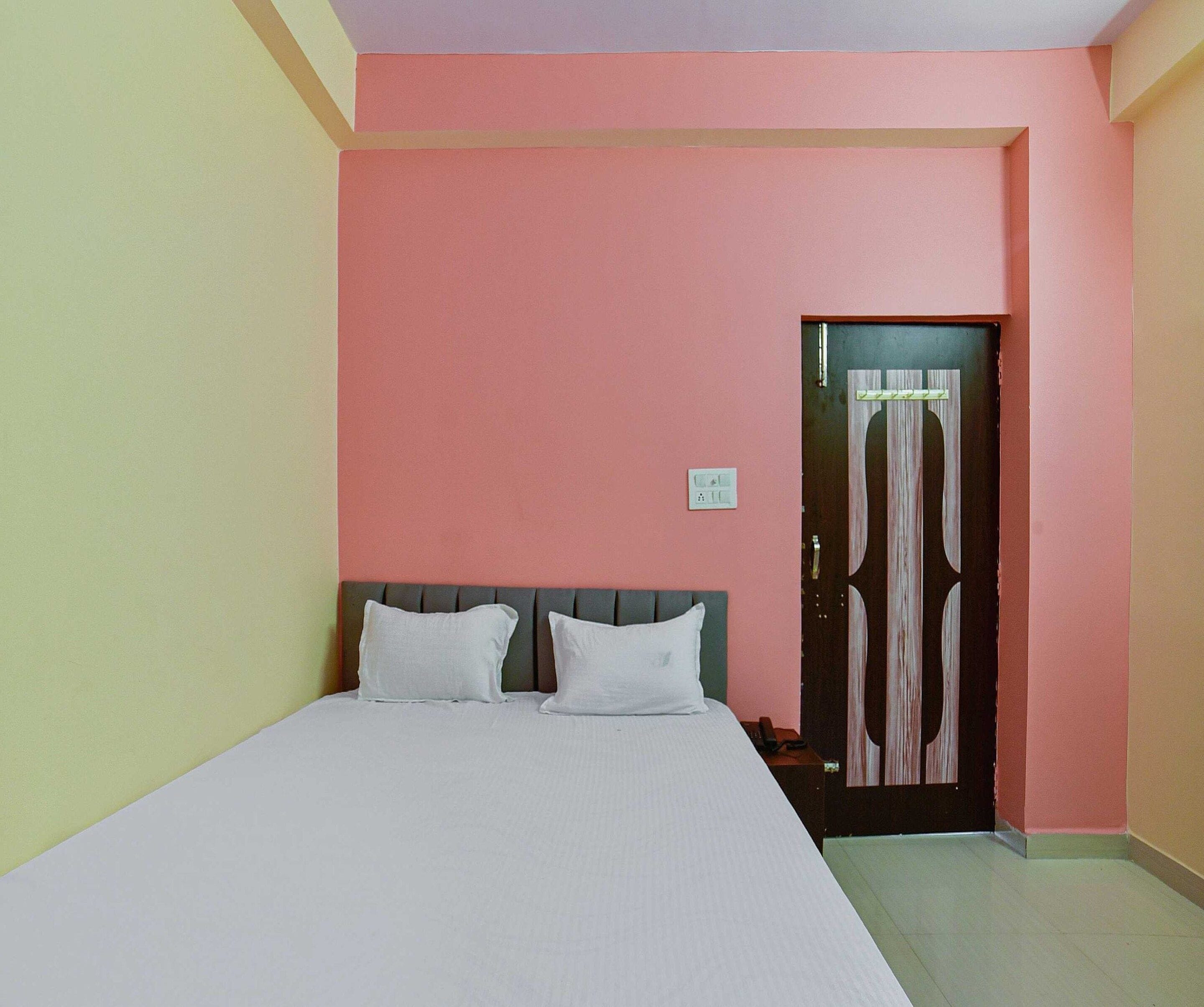 A room with a bed, a door with a curtain, and a light switch on the wall.