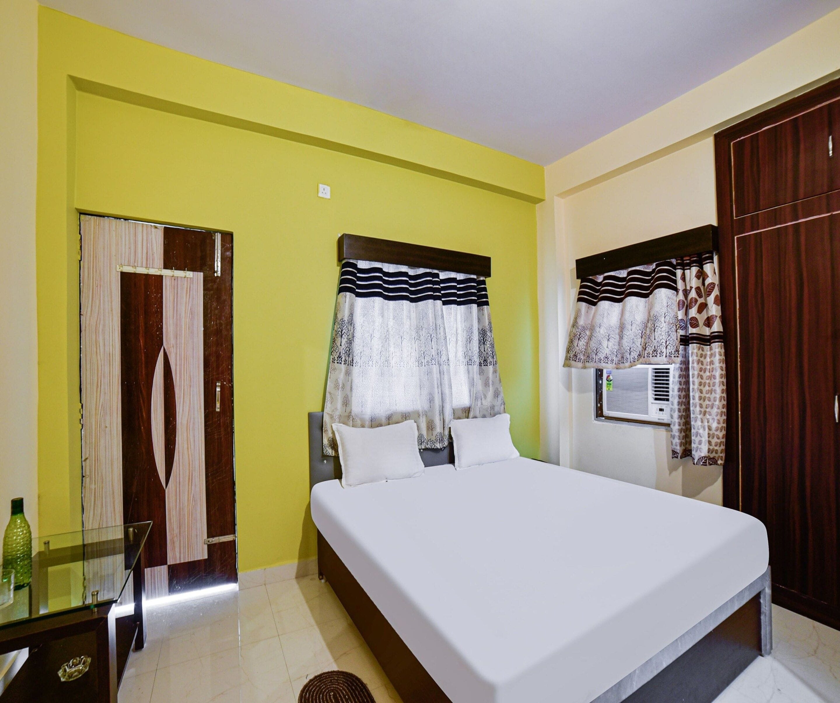 A bedroom with a bed, a window with curtains, a wardrobe, and a mirror.