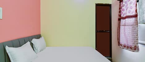 A room with a bed, a door, and a window with curtains.