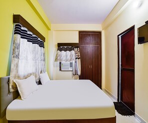 A bedroom with a bed, curtains, a wardrobe, and a door. - Deluxe Hotel Blue Velvet (Danapur)