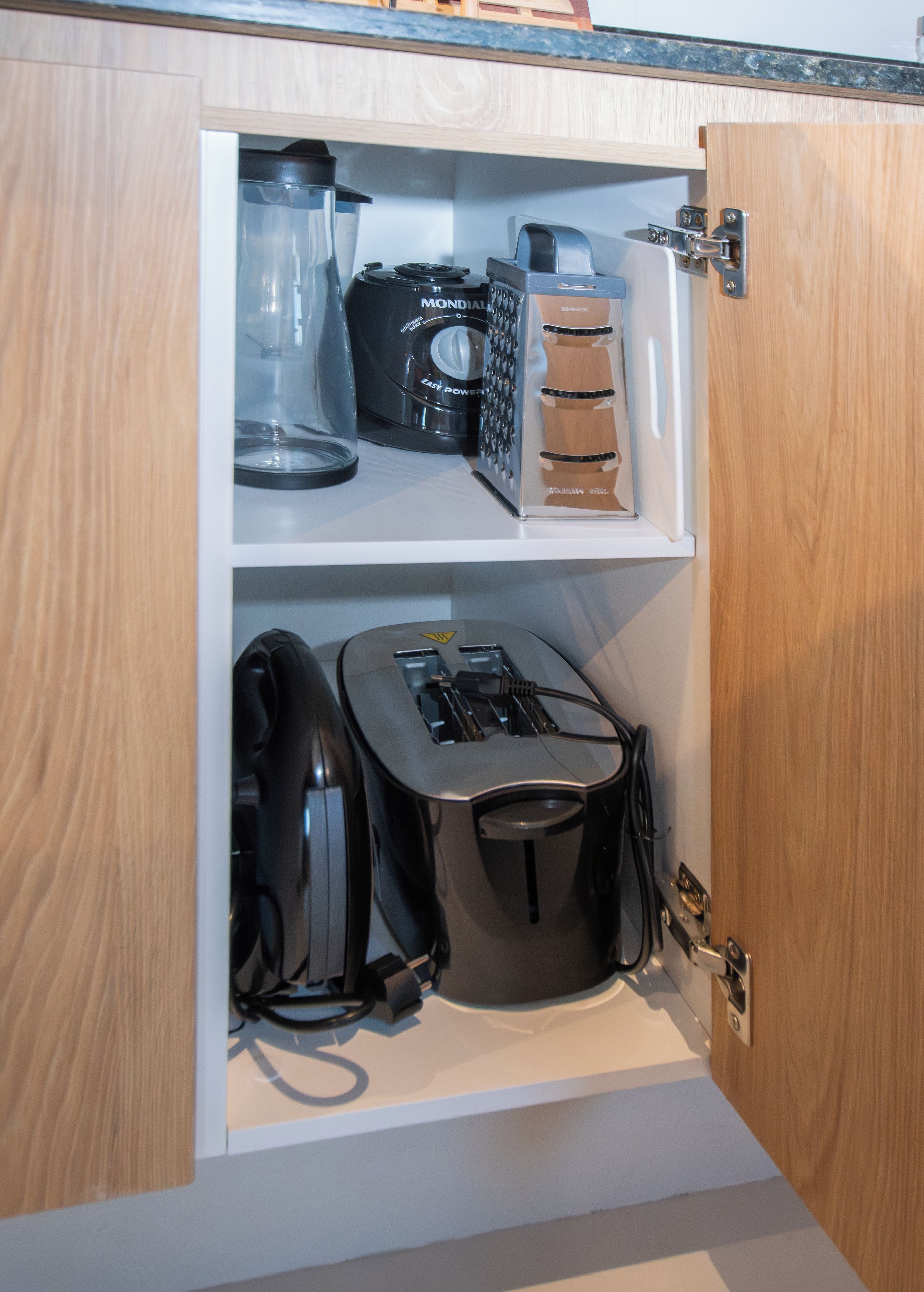 A kitchen cabinet with a coffee maker, a blender, and a toaster.