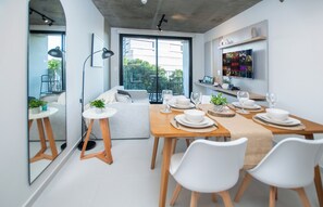 Een moderne eetruimte met een houten tafel voor vier personen, witte stoelen en een groot raam met uitzicht op het buiten.