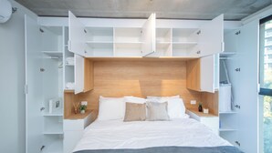 Quarto moderno com cama grande, prateleiras embutidas e vista para o exterior.