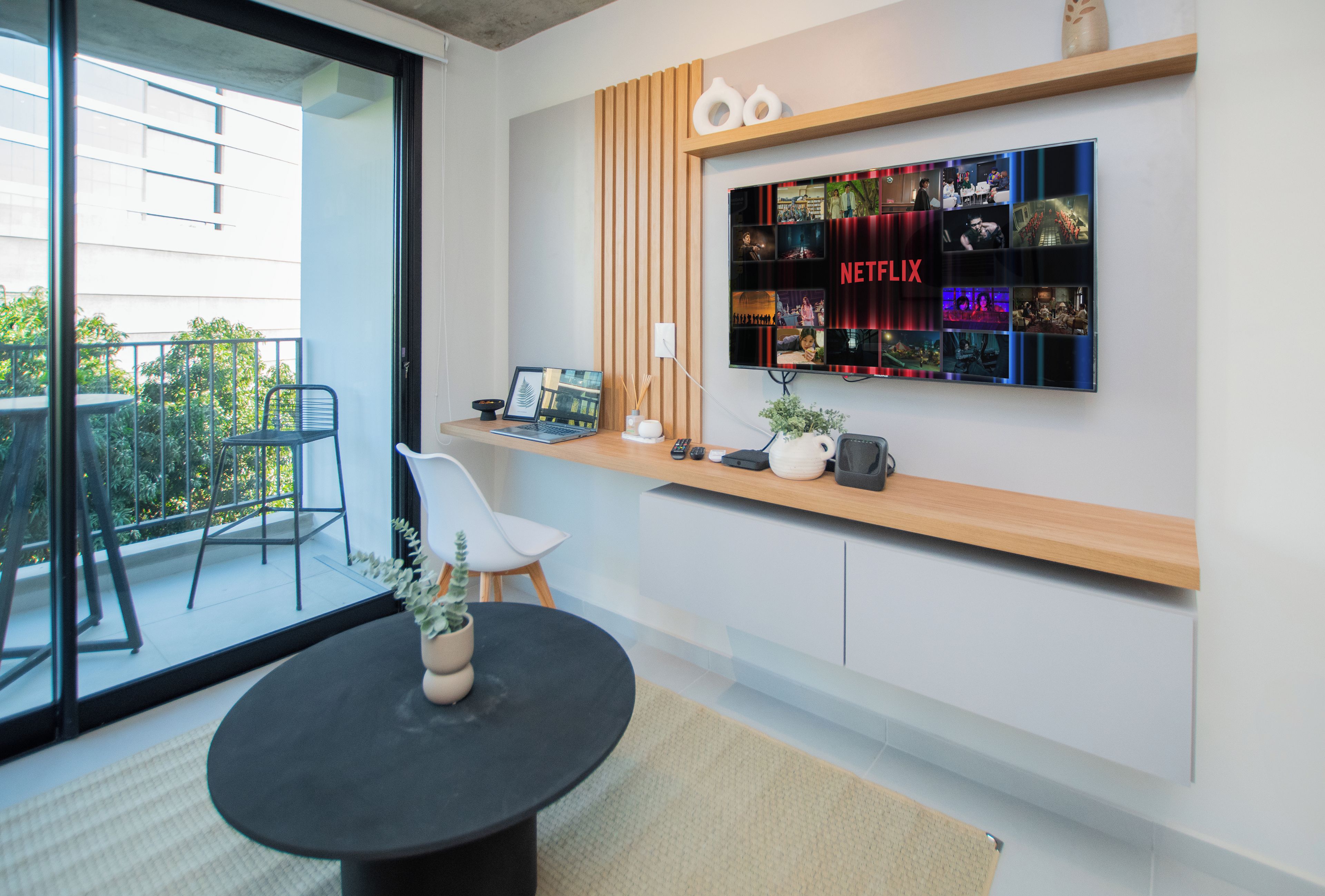 A modern living room with a large flat-screen TV mounted on a wooden shelf displaying a Netflix interface.