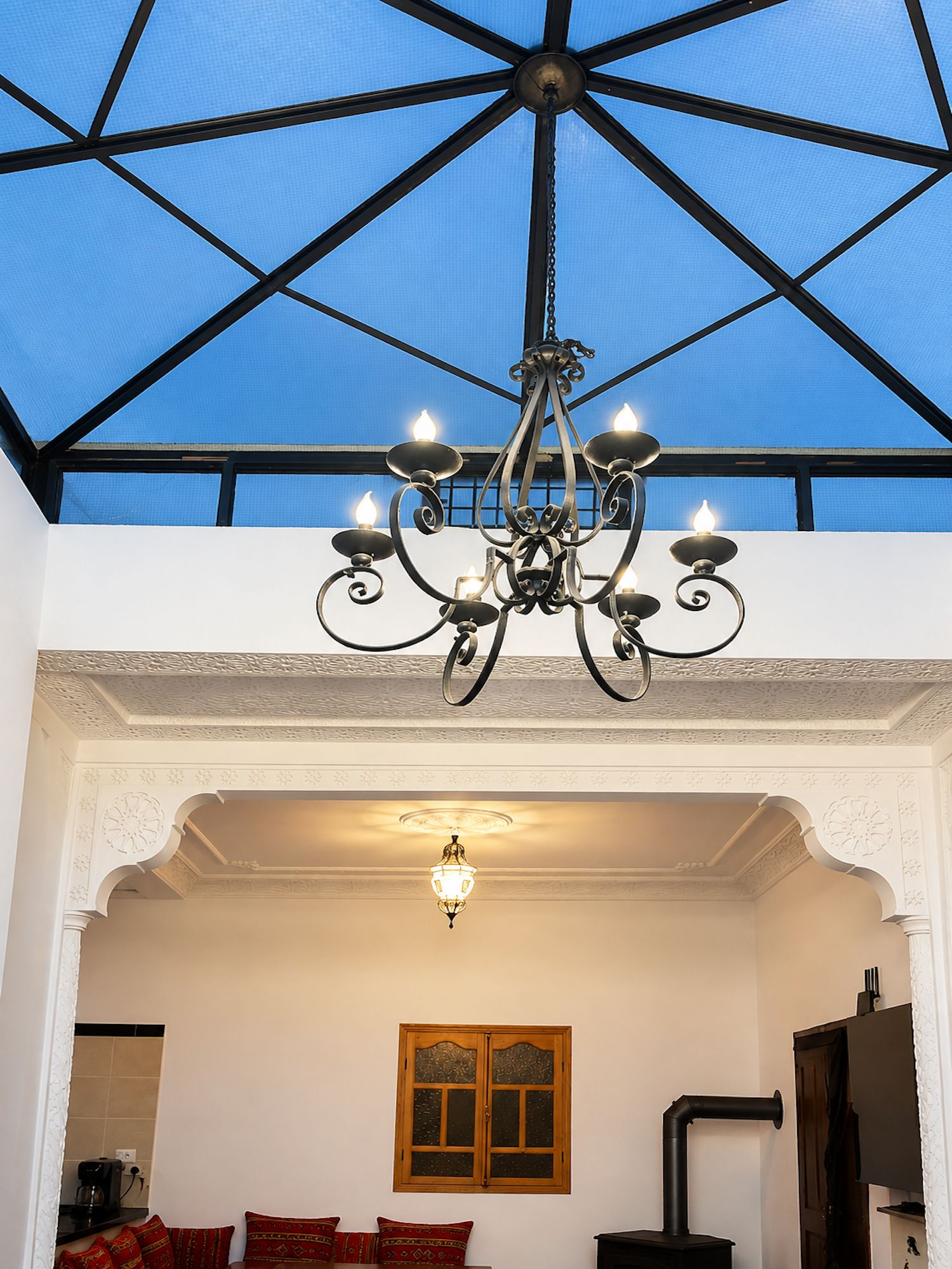 A room with a chandelier, a wooden window, and a stove.